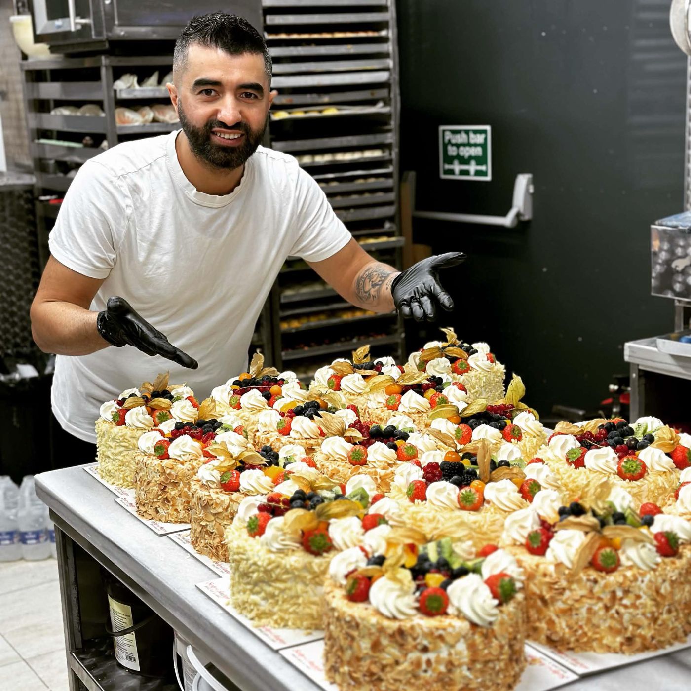 Our pastry chef with a table full of fruit-topped cakes